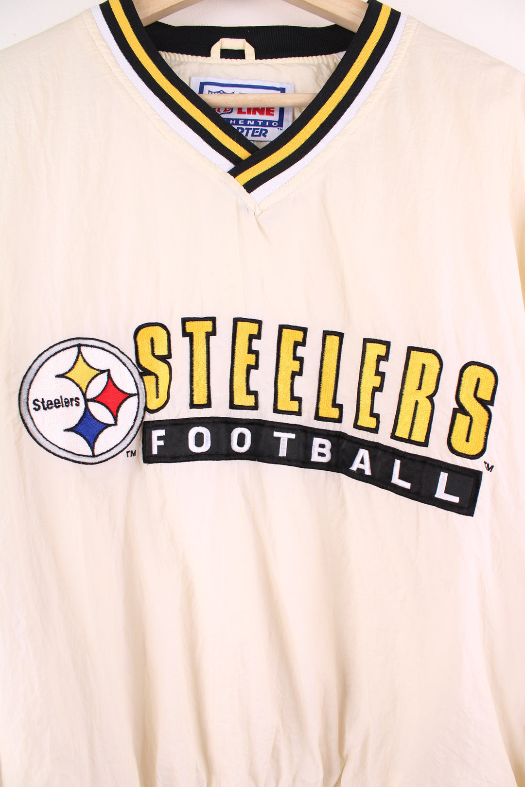 Vintage Pittsburg Steelers cream/off white nylon pullover training top by Starter with embroidered spell-out details across the chest and logo on the cuff