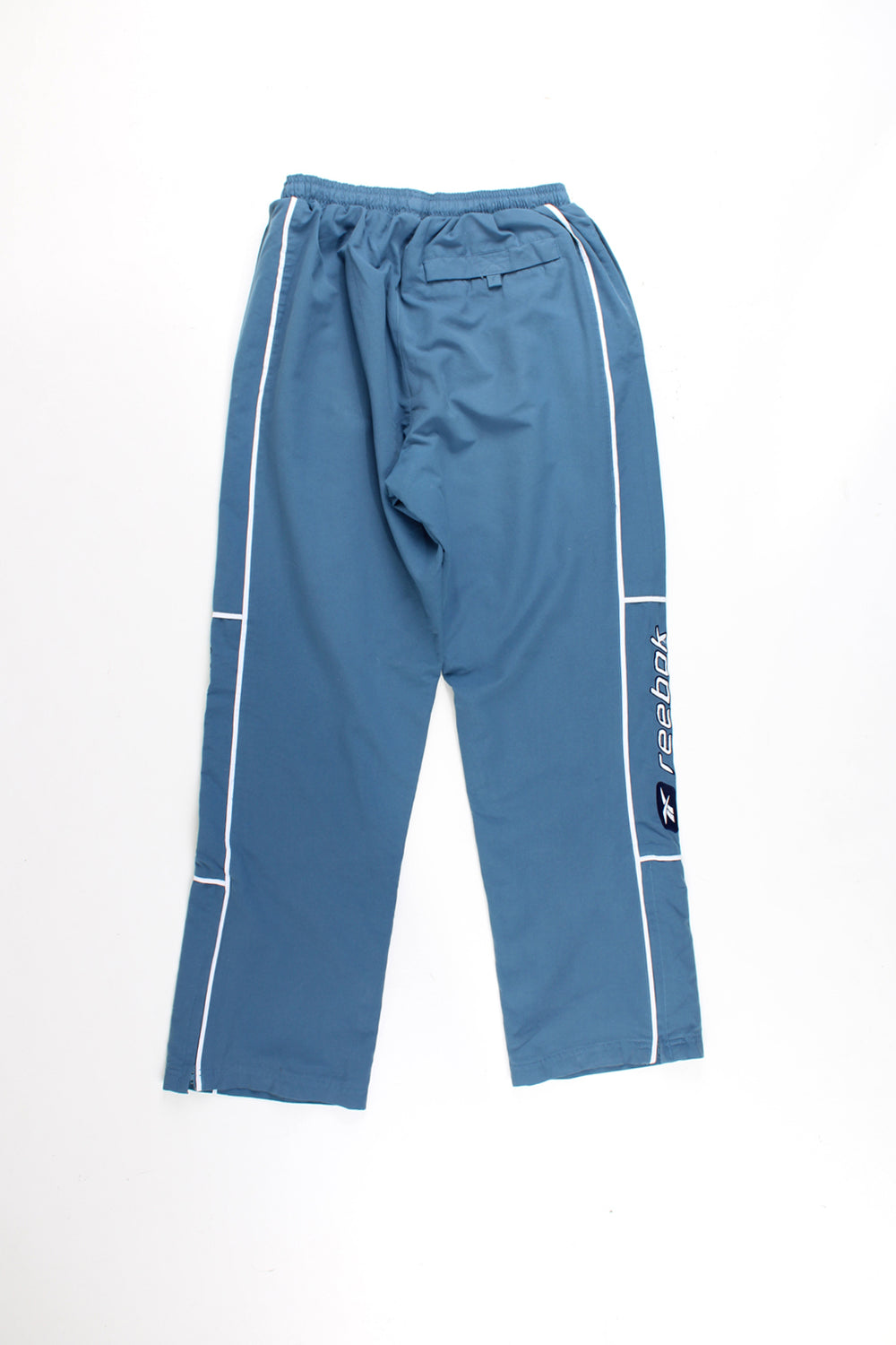 Reebok Tracksuit Bottoms in a blue colourway with white stipes and logo embroidered down the legs, and has a elasticated waist and pockets.