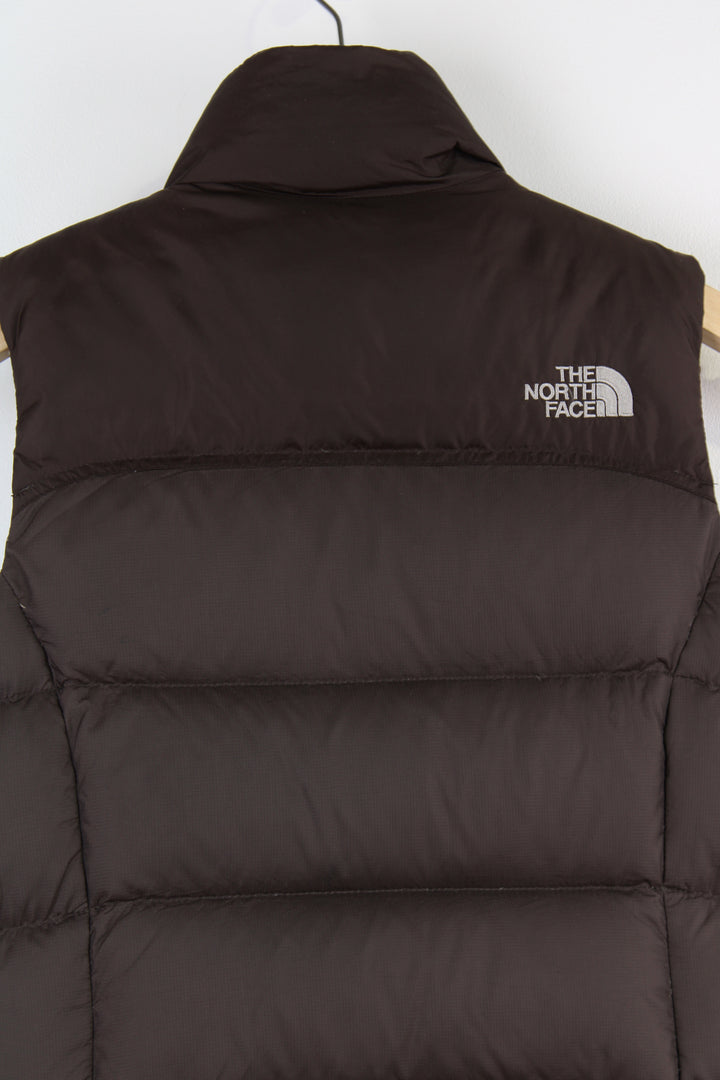 The North Face Face puffer gilet in brown, zip up with side pockets, insulated and has logo embroidered logo on the front and back.