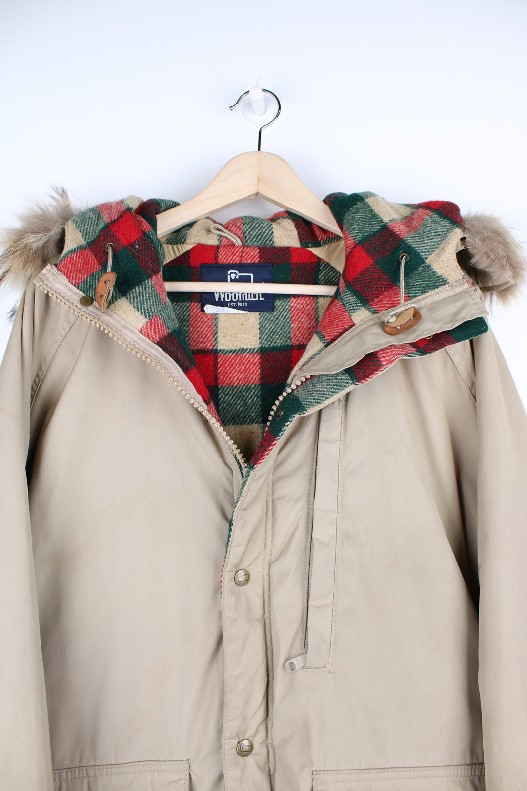 Tan Woolrich parker jacket. Features plaid wool lining, real fur trim on the hood and closes with a zip and popper buttons. good condition - small marks throughout (see photos) Size in Label: Mens L