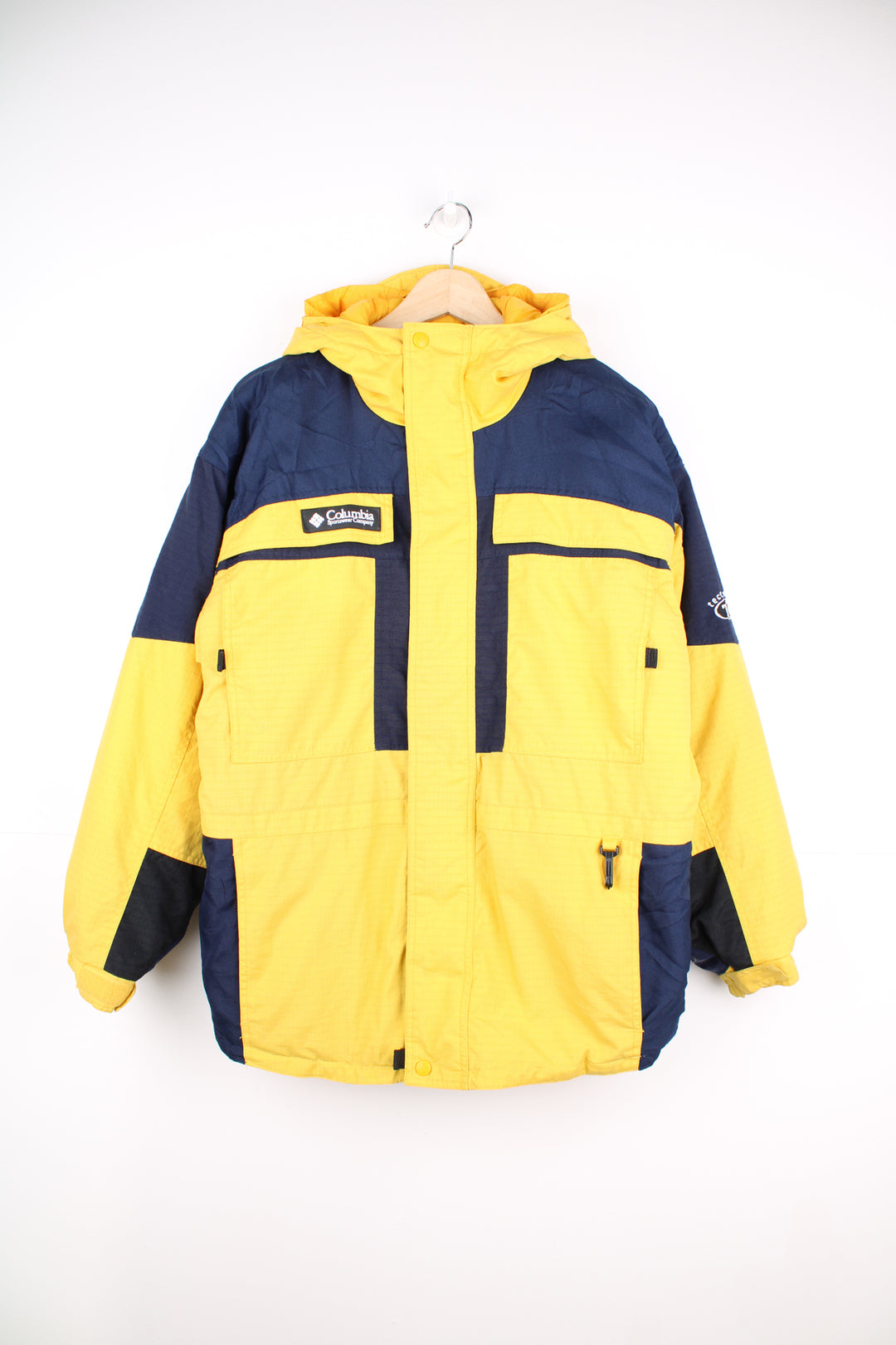 Columbia Tectonite Jacket in a yellow and navy blue colourway, zip up, multiple pockets, insulated lining, hooded and has the logo embroidered on the front.