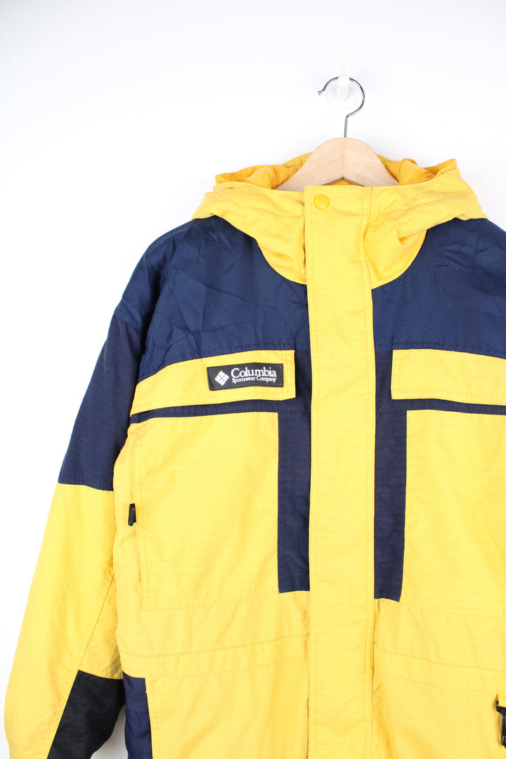 Columbia Tectonite Jacket in a yellow and navy blue colourway, zip up, multiple pockets, insulated lining, hooded and has the logo embroidered on the front.