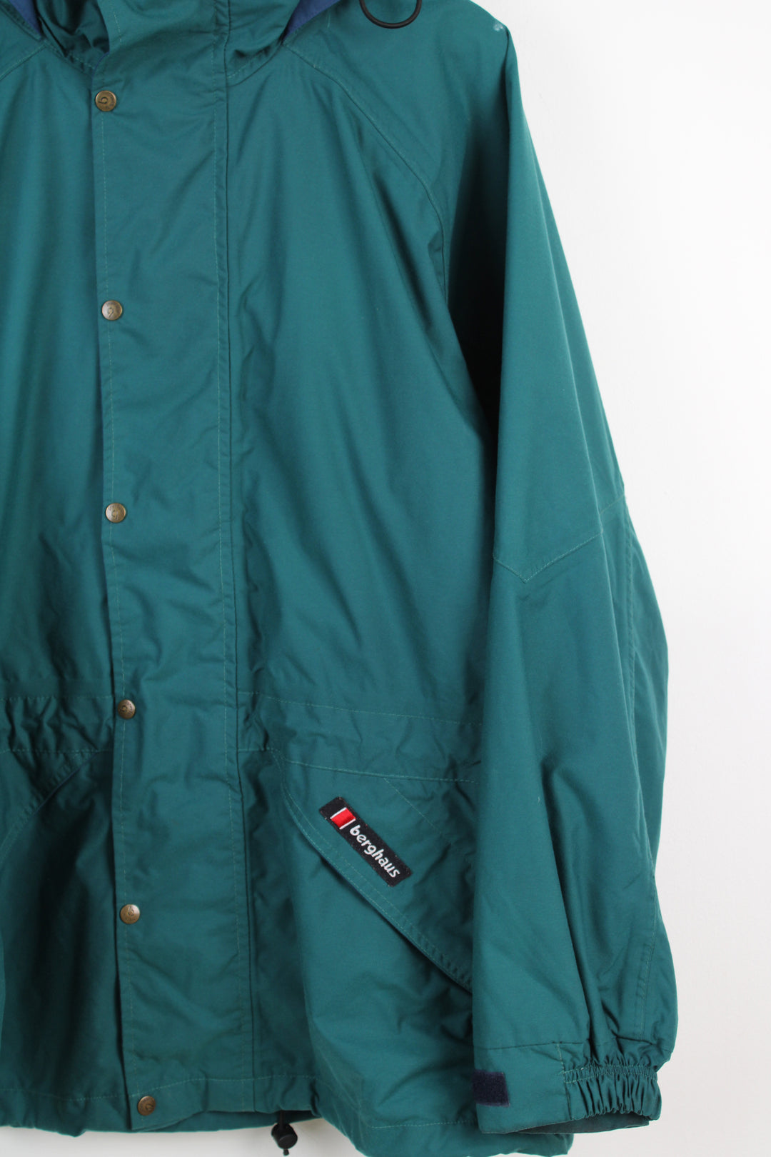 Vintage Berghaus 'Palisade I.A' green outdoor jacket with embroidered logo on the pocket, drawstring waist and hood.