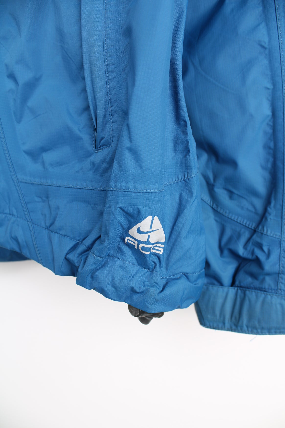 Nike ACG Lightweight Jacket in a blue colourway, zip up, side pockets, hooded and has the logo embroidered on the front and right sleeve.