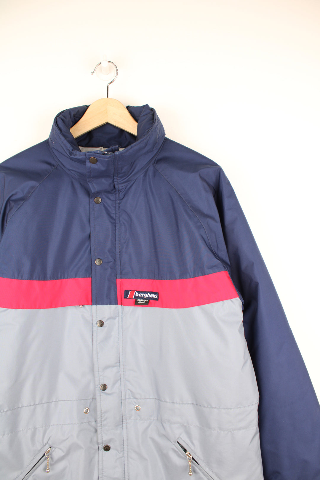 Berghaus Goretex Jacket in a blue and grey colourway, zip up, multiple pockets, hidden hood, has a insulated lining and the logo embroidered on the front.