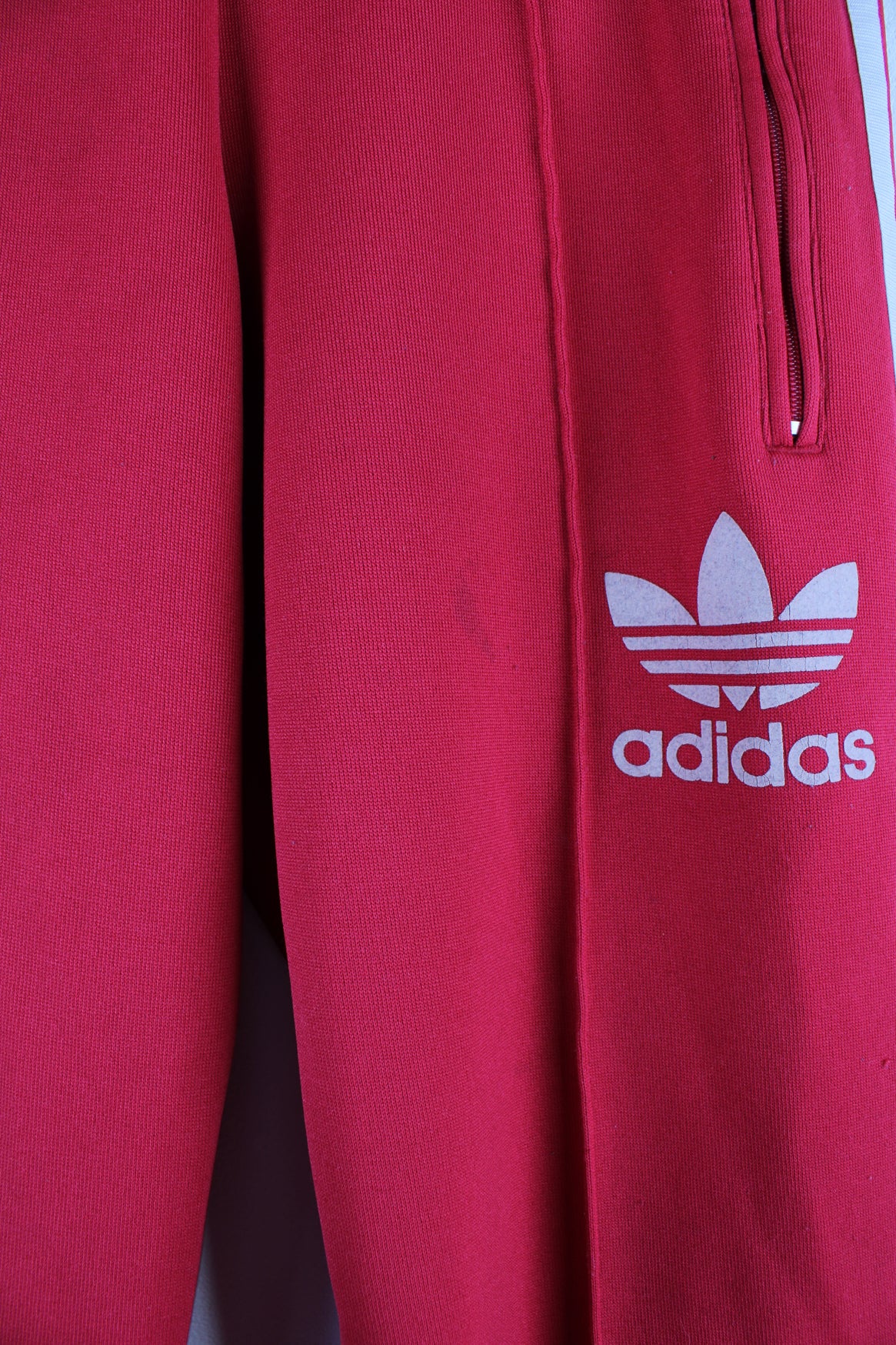 Adidas Tracksuit Bottoms in a red colourway with the iconic 3 white stripes going down the legs, has a elasticated waist, pintucked, pockets, and logo embroidered on the front.