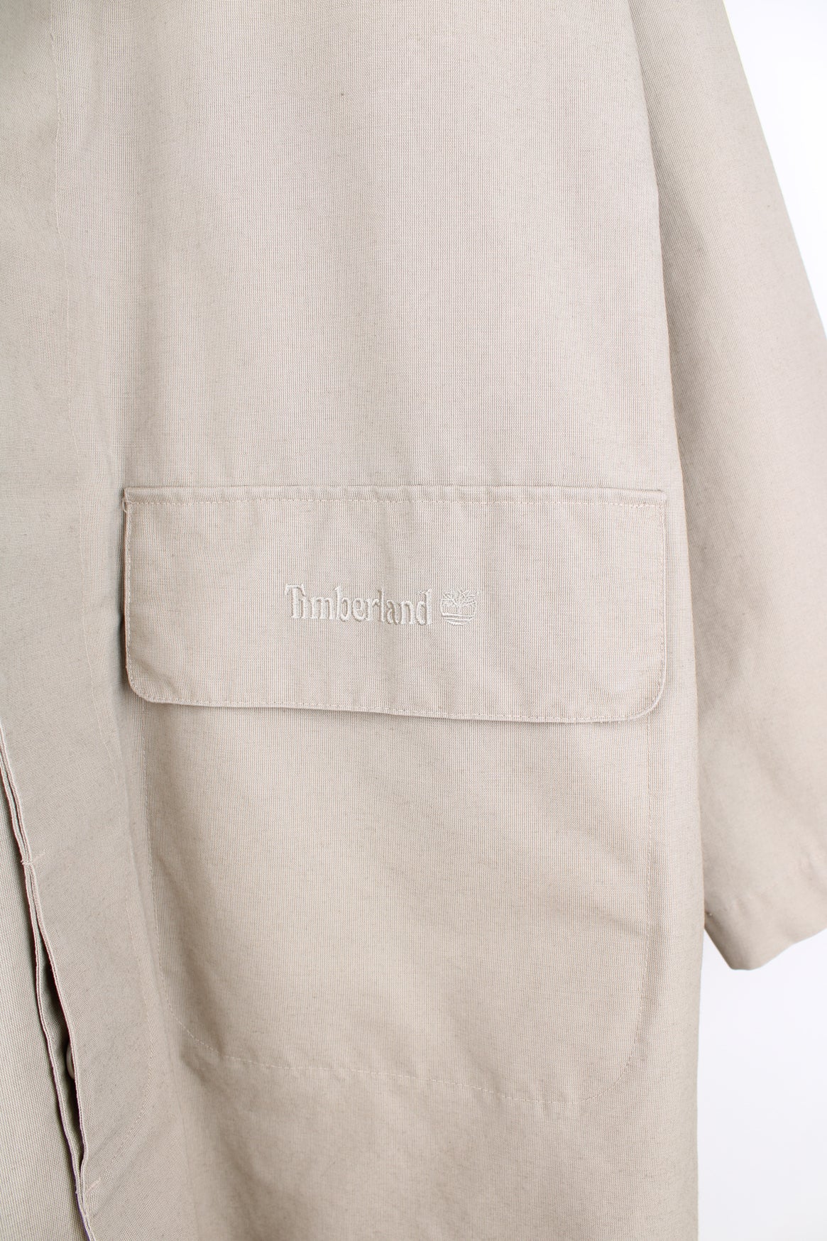 Timberland outdoor button up mac coat in tan, features embroidered spell-out logo on the pocket 