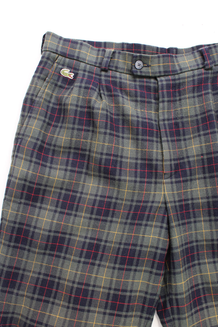 Lacoste plaid trousers in a green, blue, red and yellow colourway, multiple pockets, cuffed at the bottom and has the logo embroidered on the front.