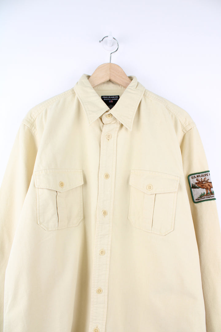 Ralph Lauren Polo Jeans Company, U.S. Wildlife Preserve Shirt in a yellow colourway, button up with double chest pockets and has a U.S. Wildlife Preserve badge embroidered on the left sleeve.