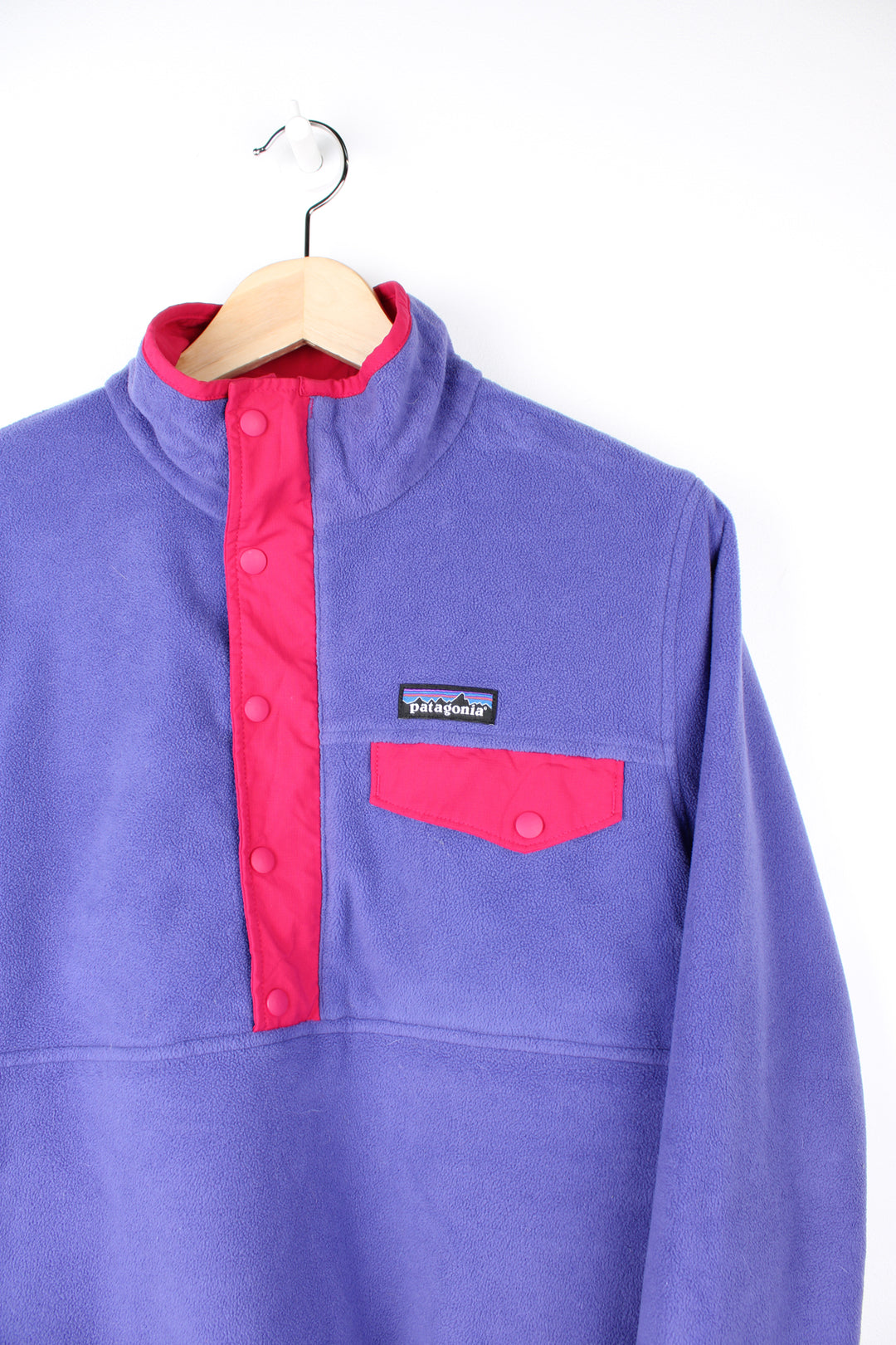 Patagonia Reversible Fleece in either a purple or pink colourway with a fleece or shell option, half zip, pockets and has the logo embroidered on the front.