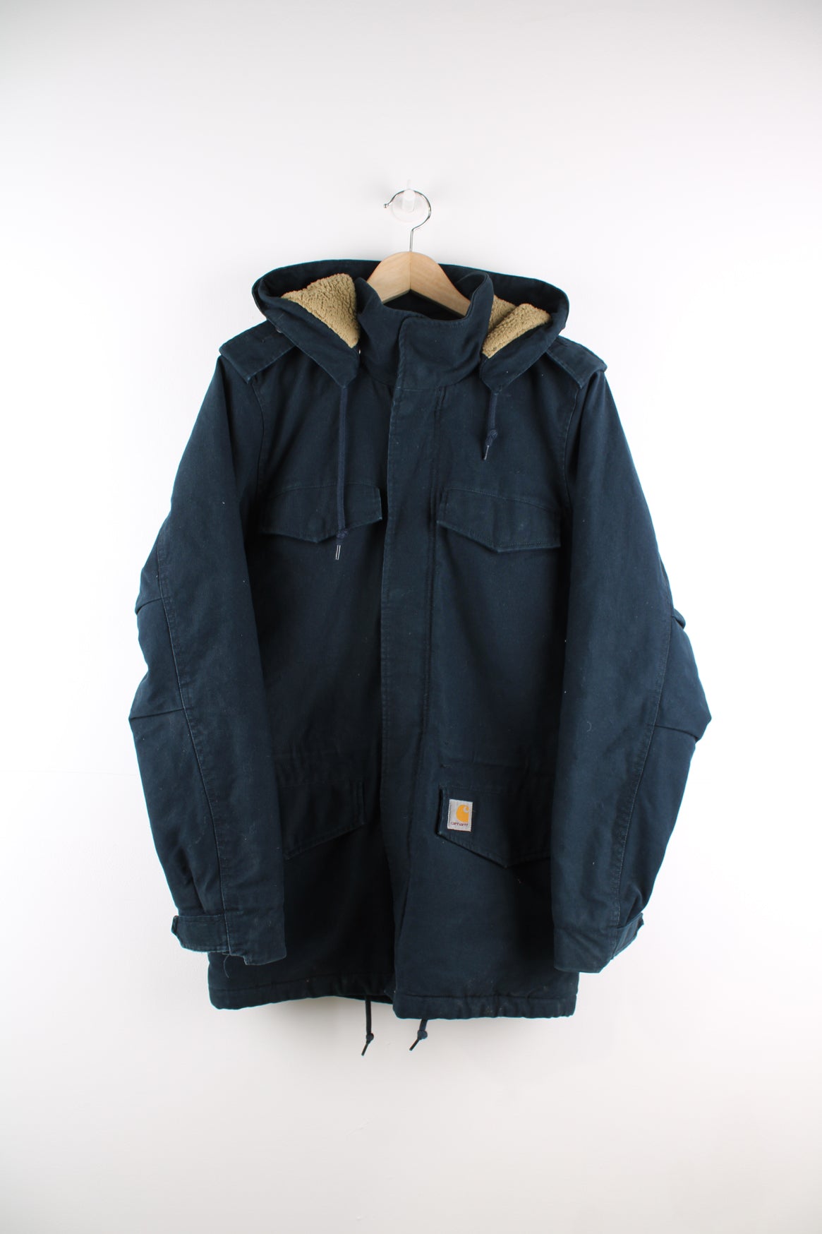 Carhartt Parka Jacket in a blue colourway, zip up, multiple pockets, detachable hood, sherpa lining, and has the logo embroidered on the front.