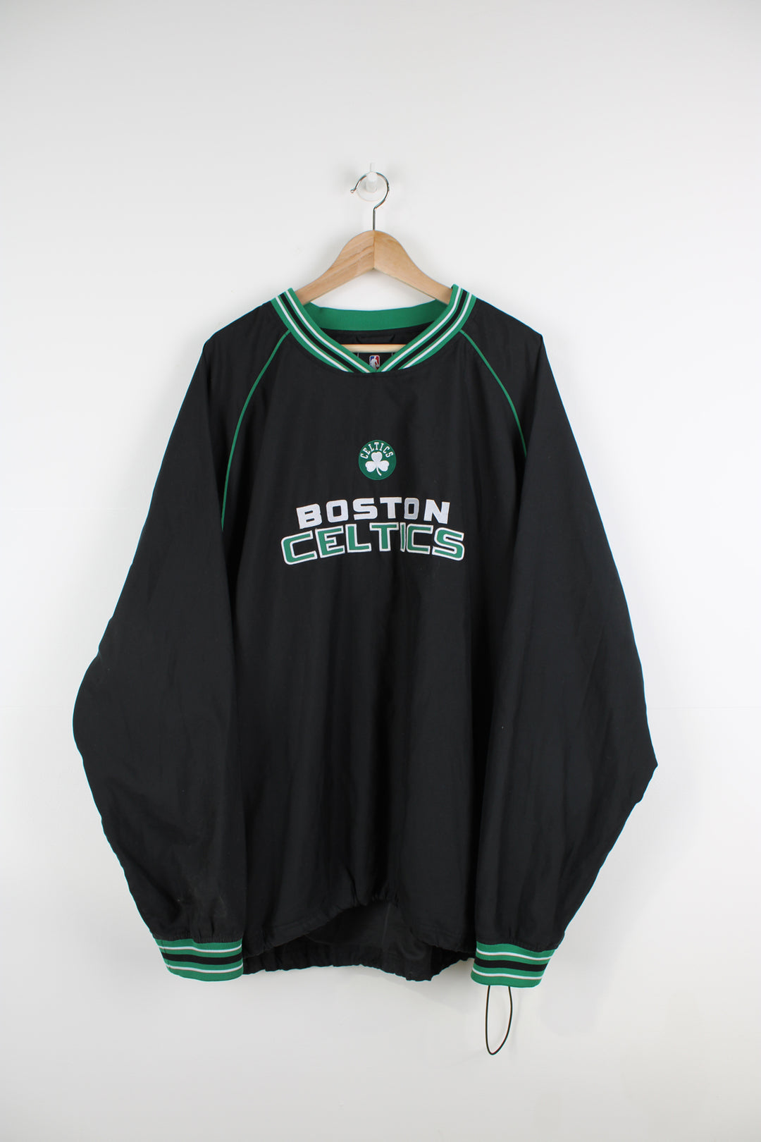 Boston Celtics all black nylon training top/pull over, by Adidas. Features embroidered spell-out logo across the chest, pockets and drawstring waist