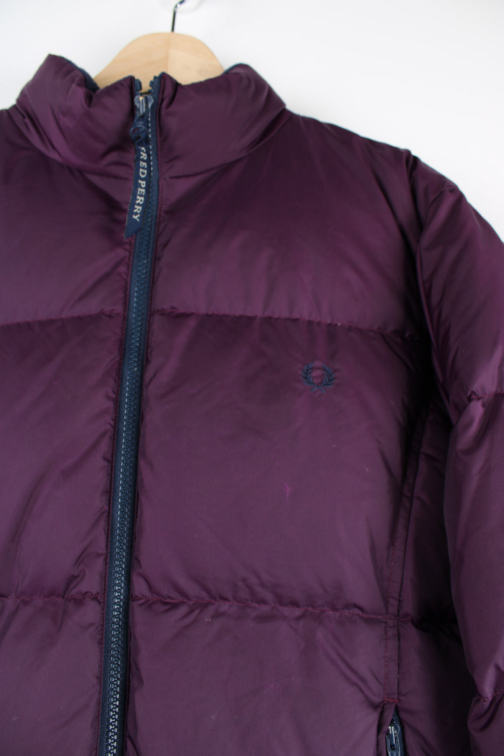 Fred Perry purple puffer jacket features embroidered logo on the chest and drawstring hem