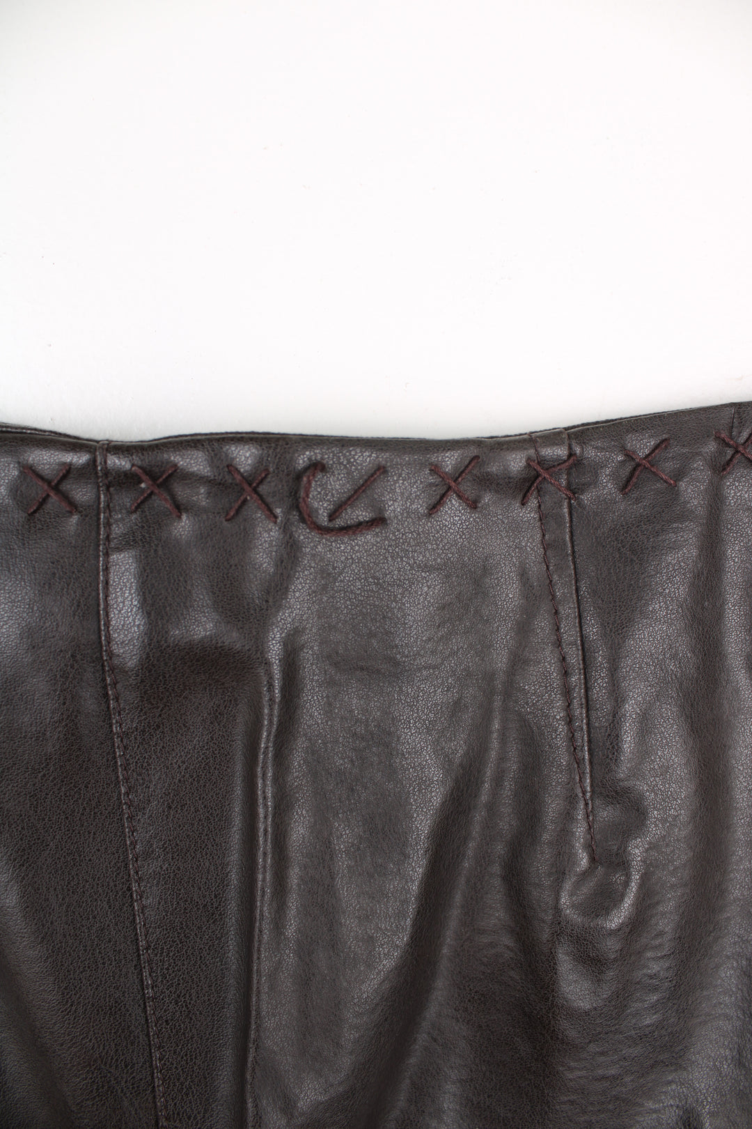 Vintage Leather Trousers in a brown colourway, mid rise, and has cross stitching design going around the waist and down the side of the legs.