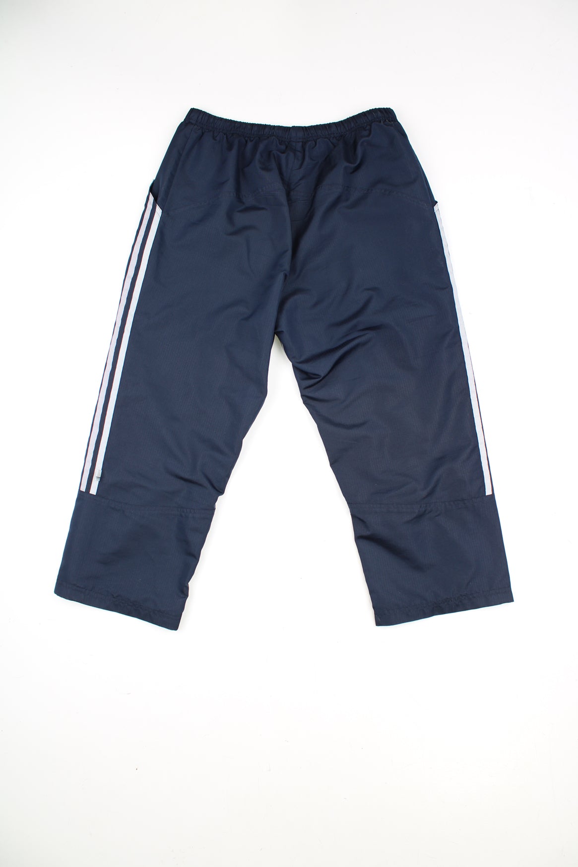 Adidas Tracksuit Bottoms in a navy blue colourway with grey three stripes going down the sides, adjustable waist, side pockets, and has the logo embroidered on the front.