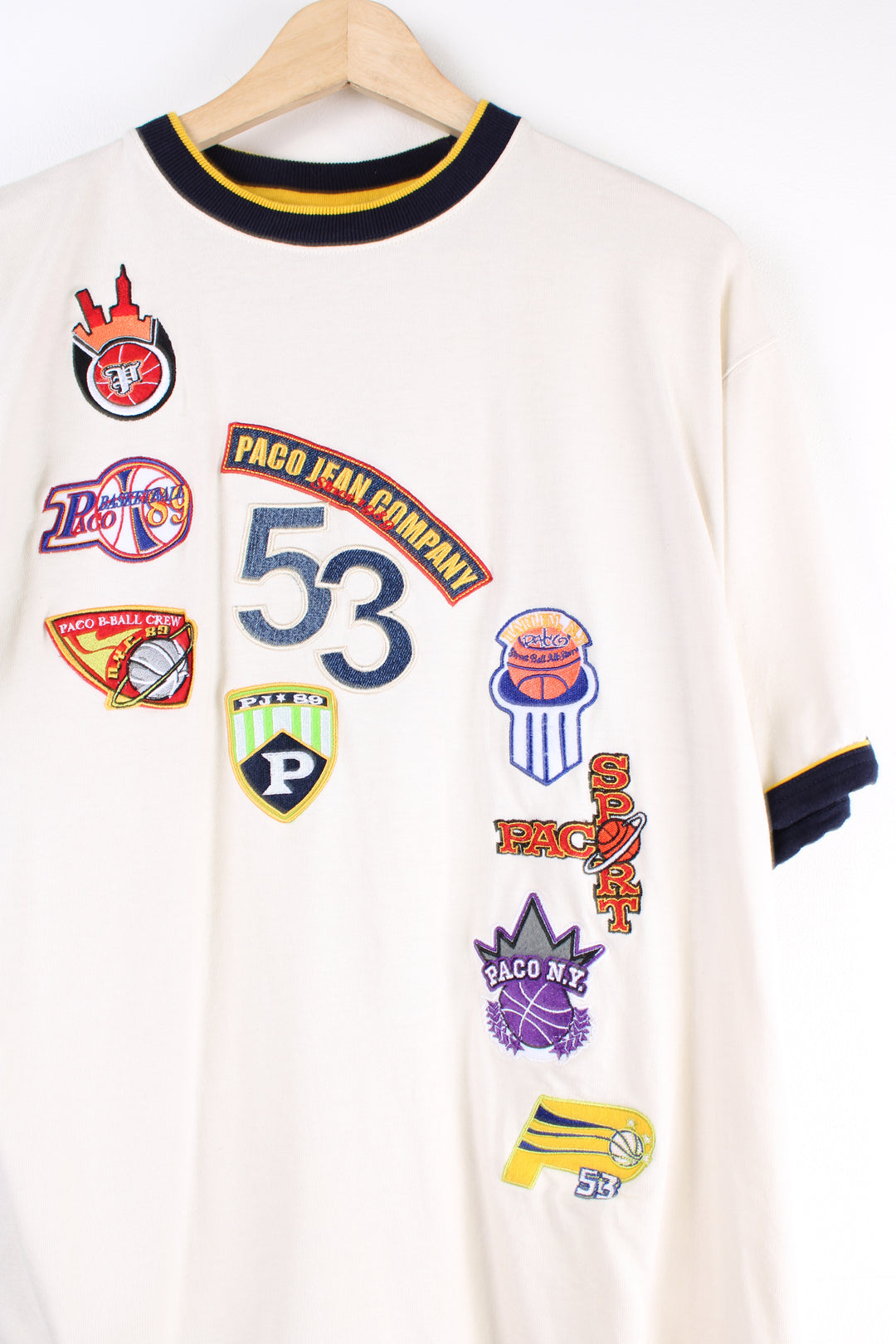 Paco Jean Company cream ringer t-shirt features embroidered badges all over the front