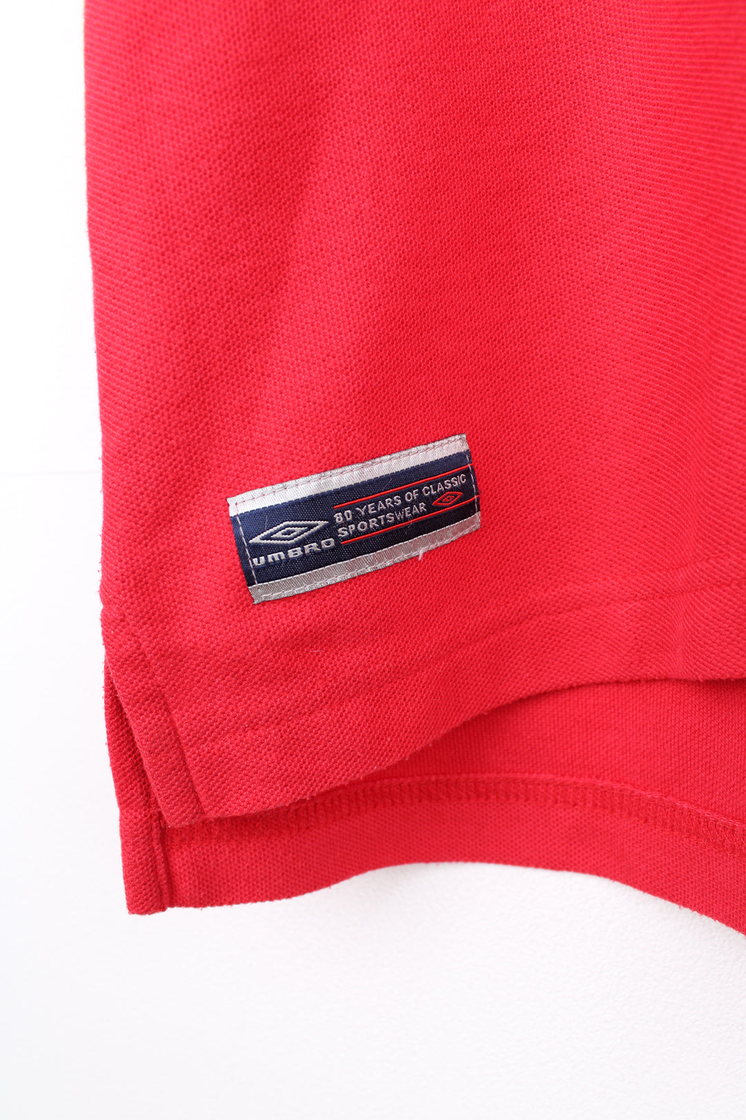 Umbro Polo Shirt in a red colourway with blue and white stripes going round the collar and shoulders, button up collar, short sleeved and has the logo embroidered on the front and back.