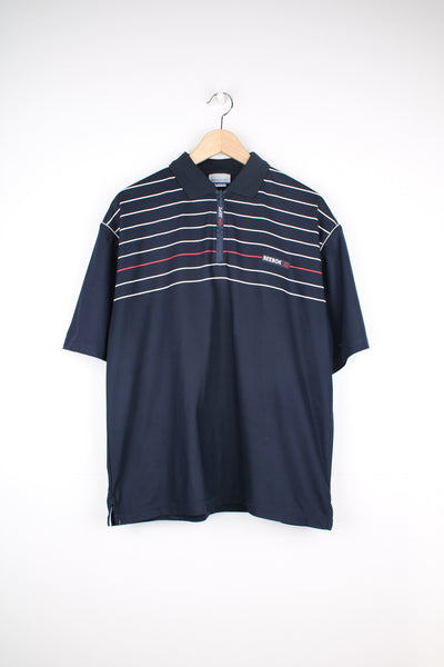 Reebok Athletic Polo Shirt in a navy blue colourway with white and red stripes going across the chest, zip up collar, short sleeved and has the logo spell out embroidered on the front.