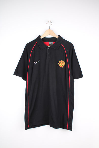 Manchester United, Nike Polo Shirt in a black and red colourway, button up collar, short sleeved and has the logos embroidered on the front.