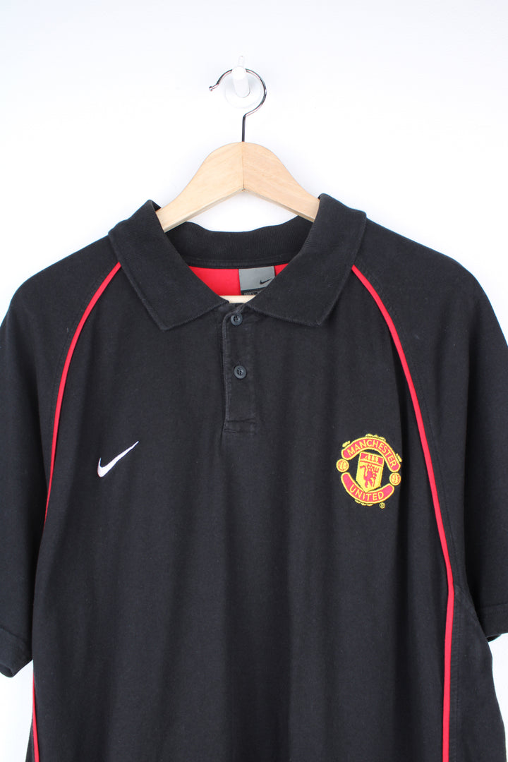 Manchester United, Nike Polo Shirt in a black and red colourway, button up collar, short sleeved and has the logos embroidered on the front.