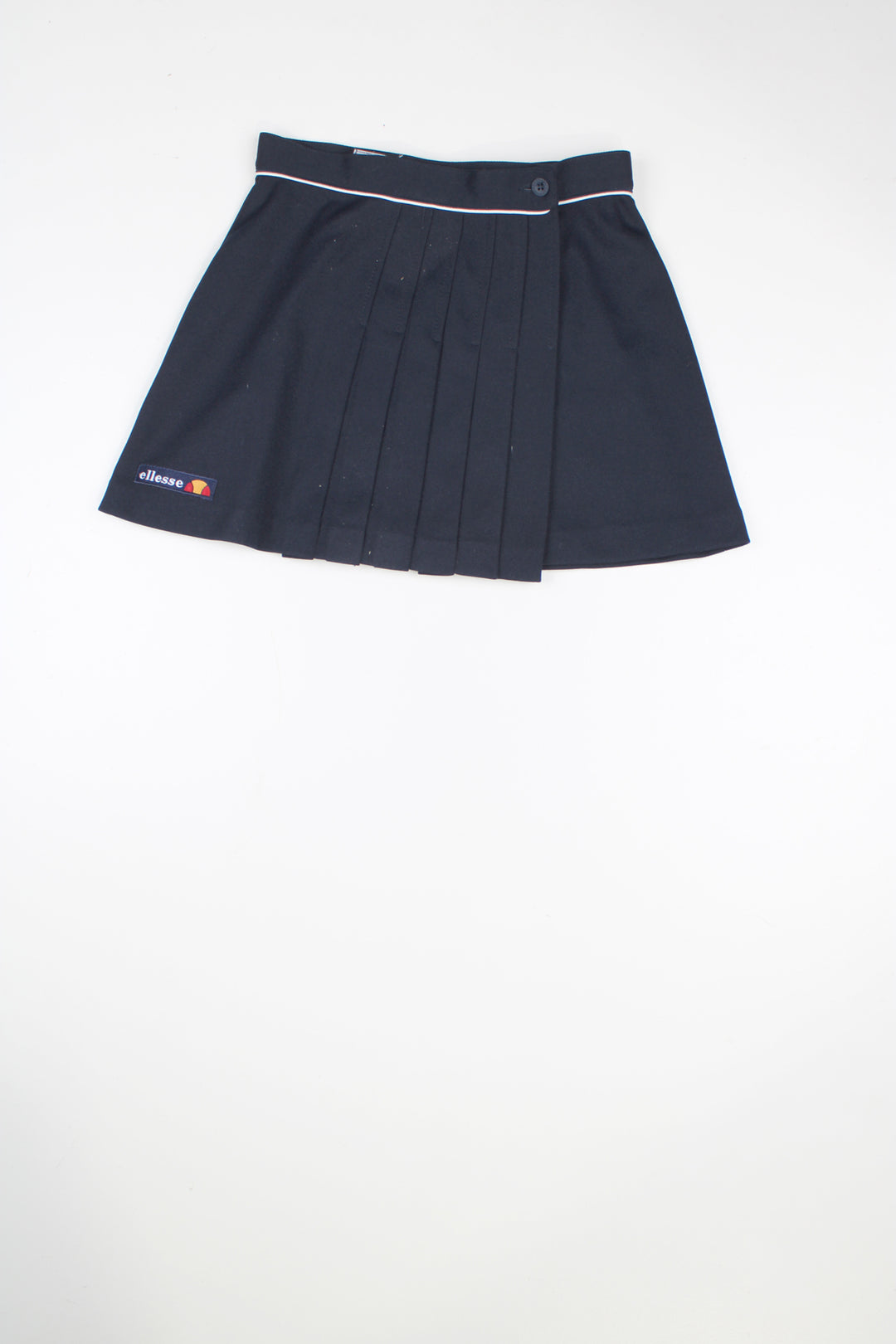 80's Navy blue Ellesse pleated tennis skirt with embroidered logo near the hem. Closes with a button on the waistband.  good condition  Size in label:  Label faded - Measures like a UK size 6