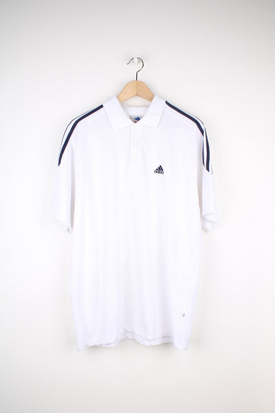 Adidas Polo Shirt in a white and navy colourway with the three stripes going around the shoulders, button up collar, short sleeved and has the logo embroidered on the front.