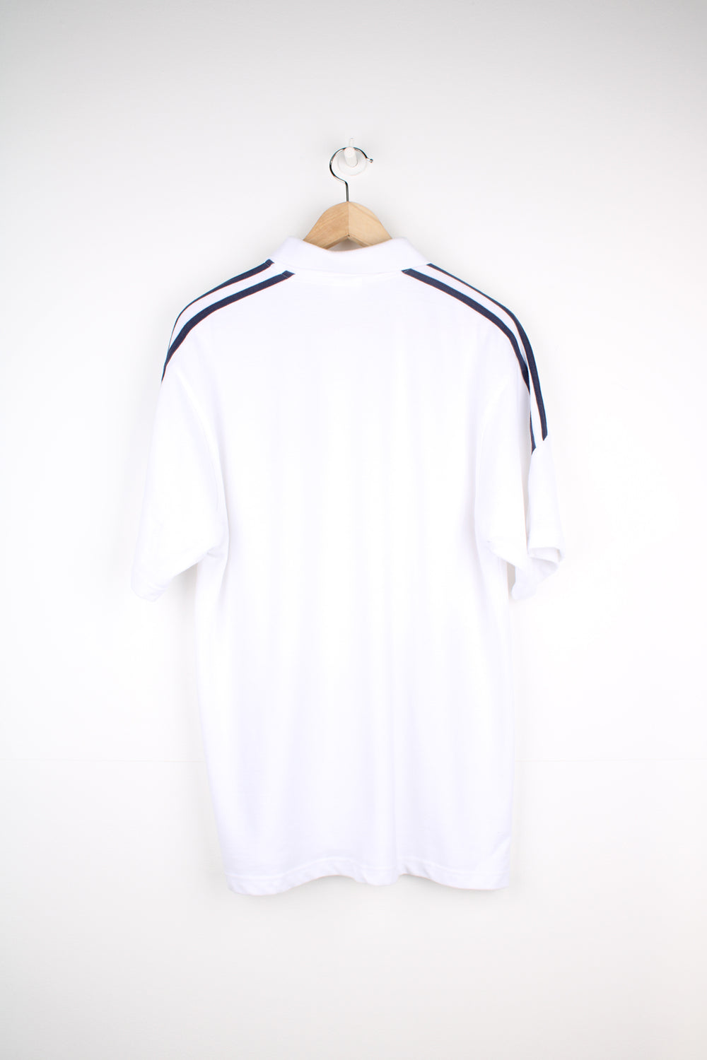 Adidas Polo Shirt in a white and navy colourway with the three stripes going around the shoulders, button up collar, short sleeved and has the logo embroidered on the front.