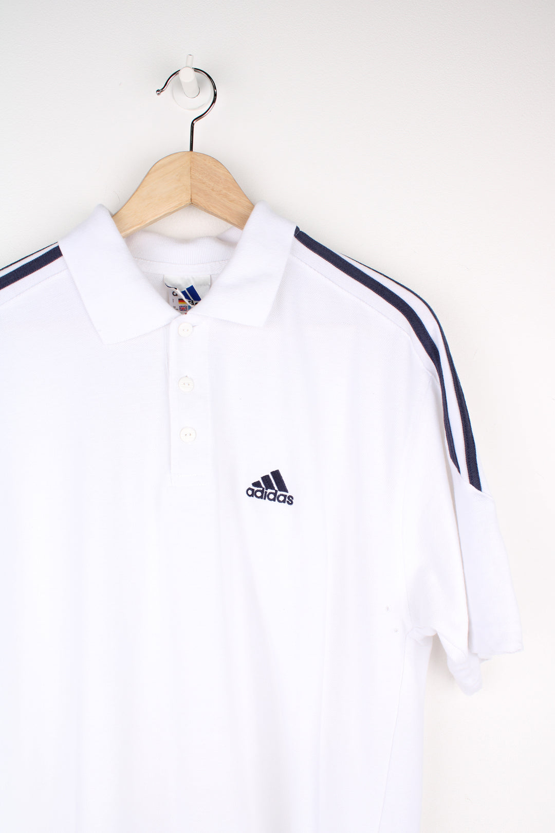 Adidas Polo Shirt in a white and navy colourway with the three stripes going around the shoulders, button up collar, short sleeved and has the logo embroidered on the front.