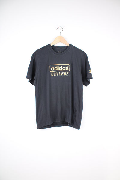 Adidas, Chile 62 T-Shirt in a black and gold colourway, short sleeve and has the logo spell out embroidered on the front and left sleeve.