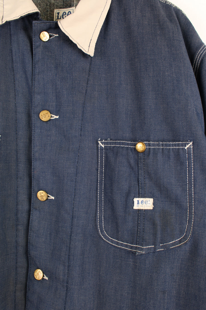 Vintage 70's Lee Denim Chore Jacket in a dark blue colourway with a tanned collar and contrast stitching throughout, button up with multiple pockets, blanket lining, and has the logo embroidered on the front.