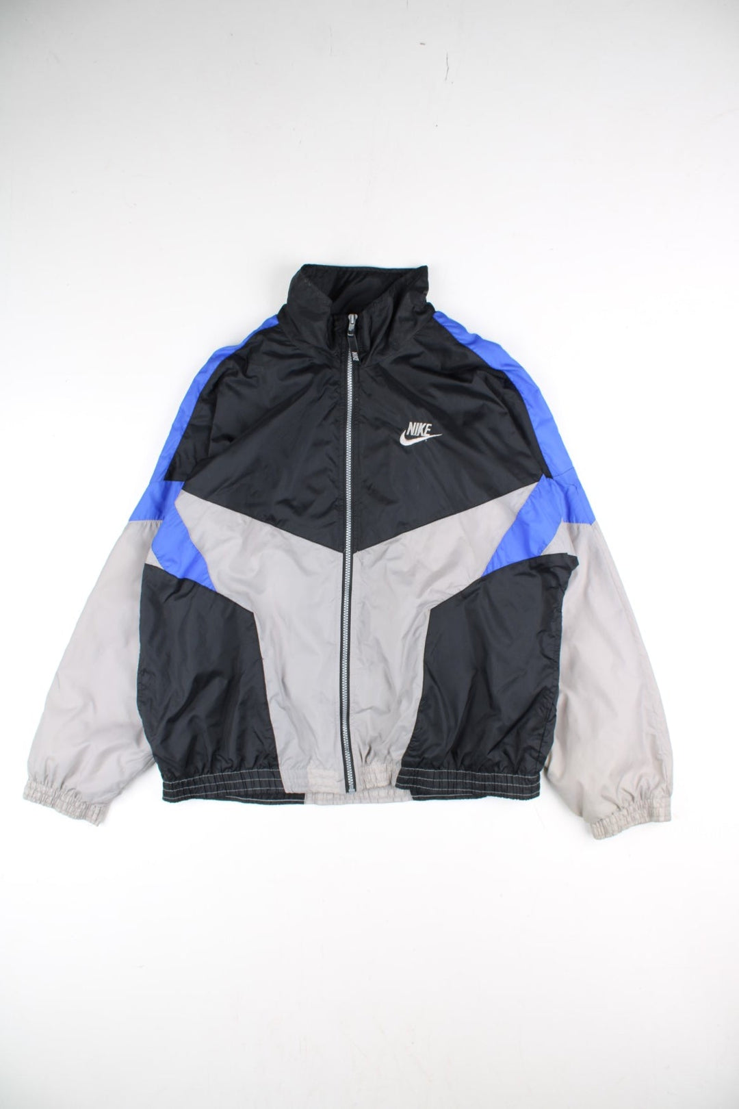 Vintage 90's Nike Tracksuit Jacket in a black, grey and blue patterned colourway. Zips up and has side pockets, and has the logo embroidered on the front.