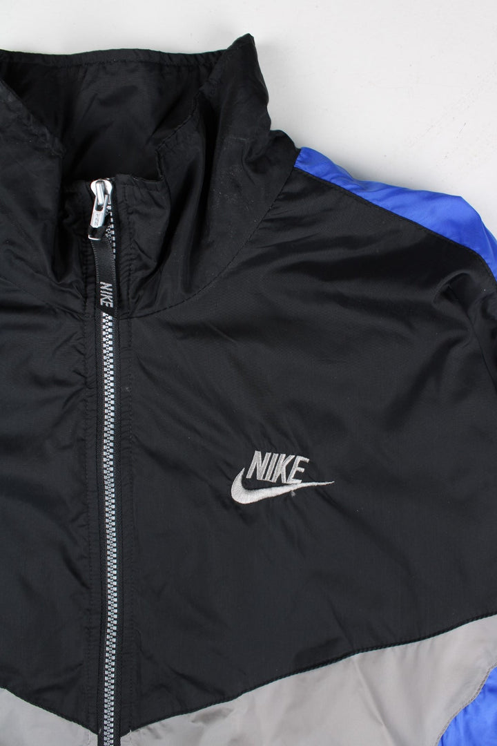 Vintage 90's Nike Tracksuit Jacket in a black, grey and blue patterned colourway. Zips up and has side pockets, and has the logo embroidered on the front.