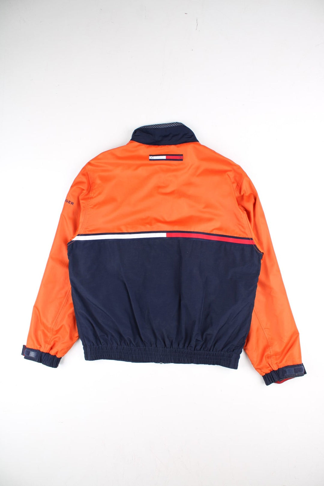 Vintage Tommy Hilfiger Windbreaker Jacket in a orange and blue colourway. Zips up and has side pockets, mesh lining, has the logo stripe going across the front and back, and the spell out embroidered on the left sleeve.