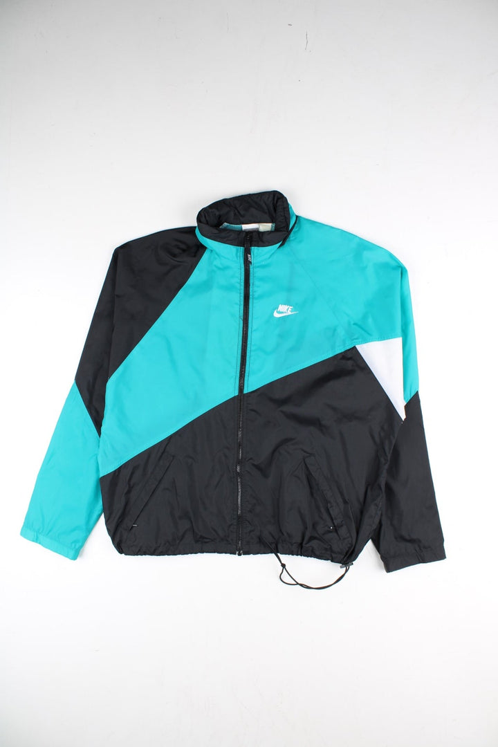 Vintage 90's Nike Tracksuit Jacket in a black and blue colourway. Zips up and has side pockets, mesh lining, and has the logo embroidered on the front.