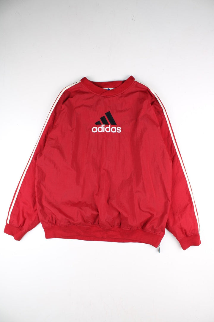 Vintage 90's Adidas Drill Training Top in a red colourway, has the iconic three stripes going down the sleeves, and on the front the logo embroidered on.