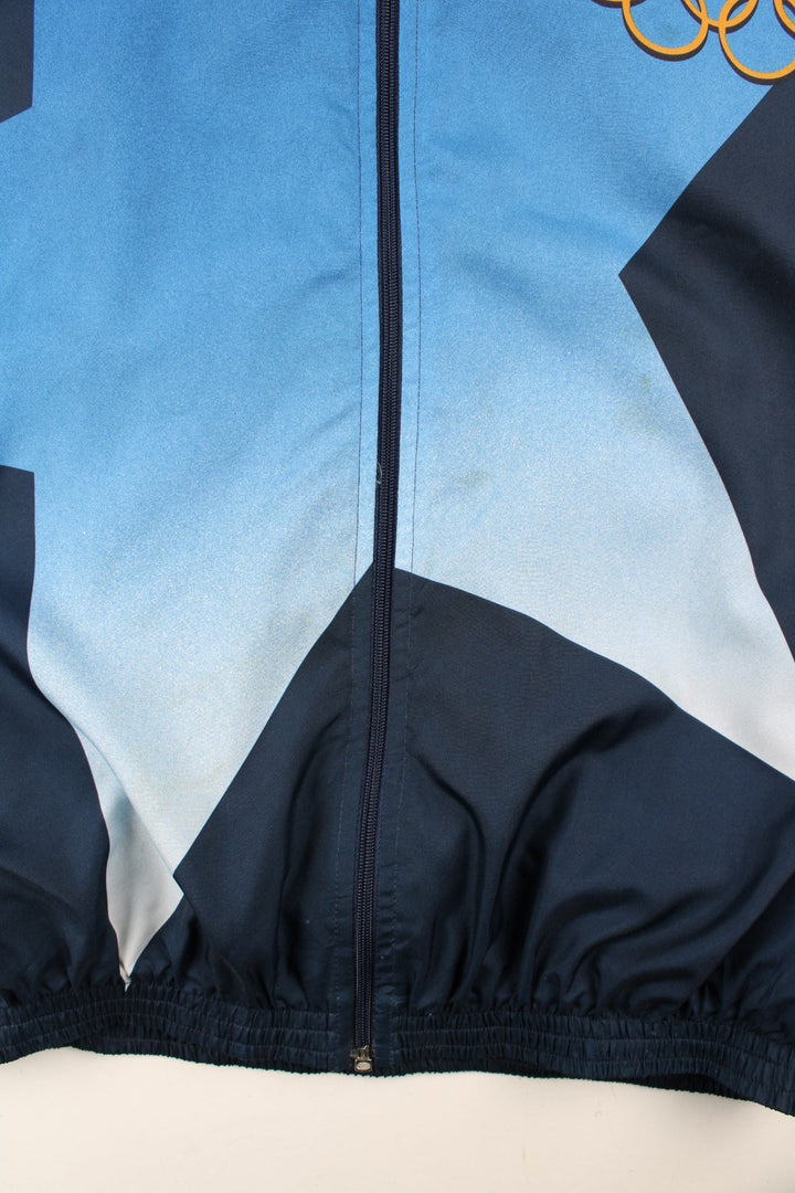 Vintage 1996 Champion USA Olympic Team Track Jacket in a blue colourway. Zips up and has side pockets, and the logos printed on the front, back and on the sleeves.