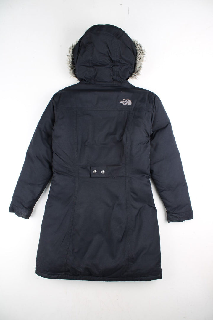 The North Face Parka Coat in a black colourway. Zips up and has multiple pockets, insulated lining, hooded with a faux fur trim, and has the logo embroidered on the front and back.