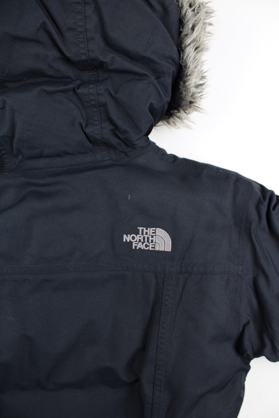 The North Face Parka Coat in a black colourway. Zips up and has multiple pockets, insulated lining, hooded with a faux fur trim, and has the logo embroidered on the front and back.