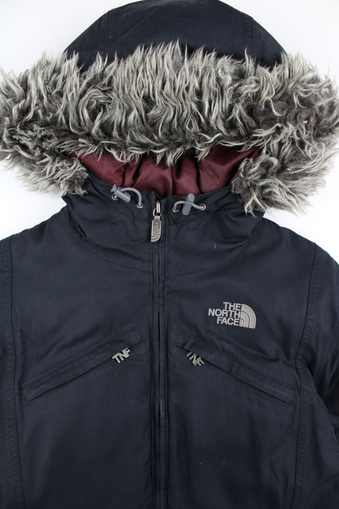 The North Face Parka Coat in a black colourway. Zips up and has multiple pockets, insulated lining, hooded with a faux fur trim, and has the logo embroidered on the front and back.