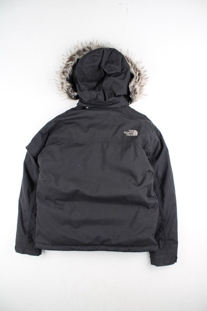 The North Face Parka Coat in a black colourway. Zips up and has multiple pockets, insulated lining, hooded with a detachable faux fur trim, and has the logo embroidered on the front and back.