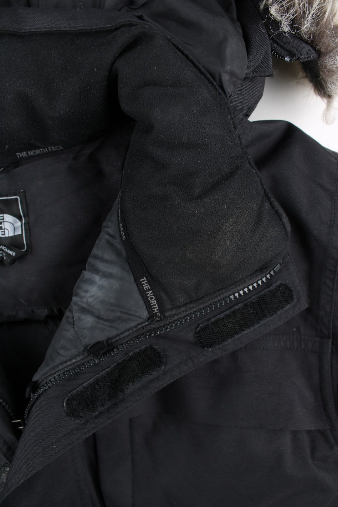 The North Face Parka Coat in a black colourway. Zips up and has multiple pockets, insulated lining, hooded with a detachable faux fur trim, and has the logo embroidered on the front and back.