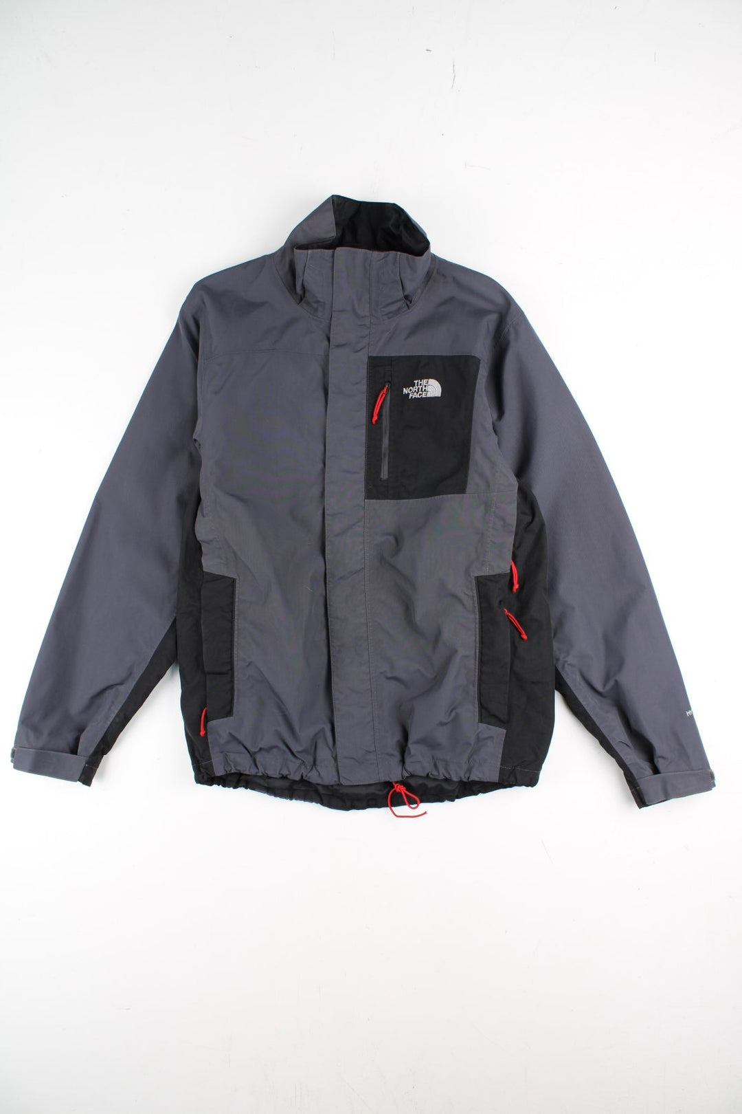 The North Face Jacket in a grey and black colourway. Zips up and has multiple pockets, and the logo embroidered on the front and back.