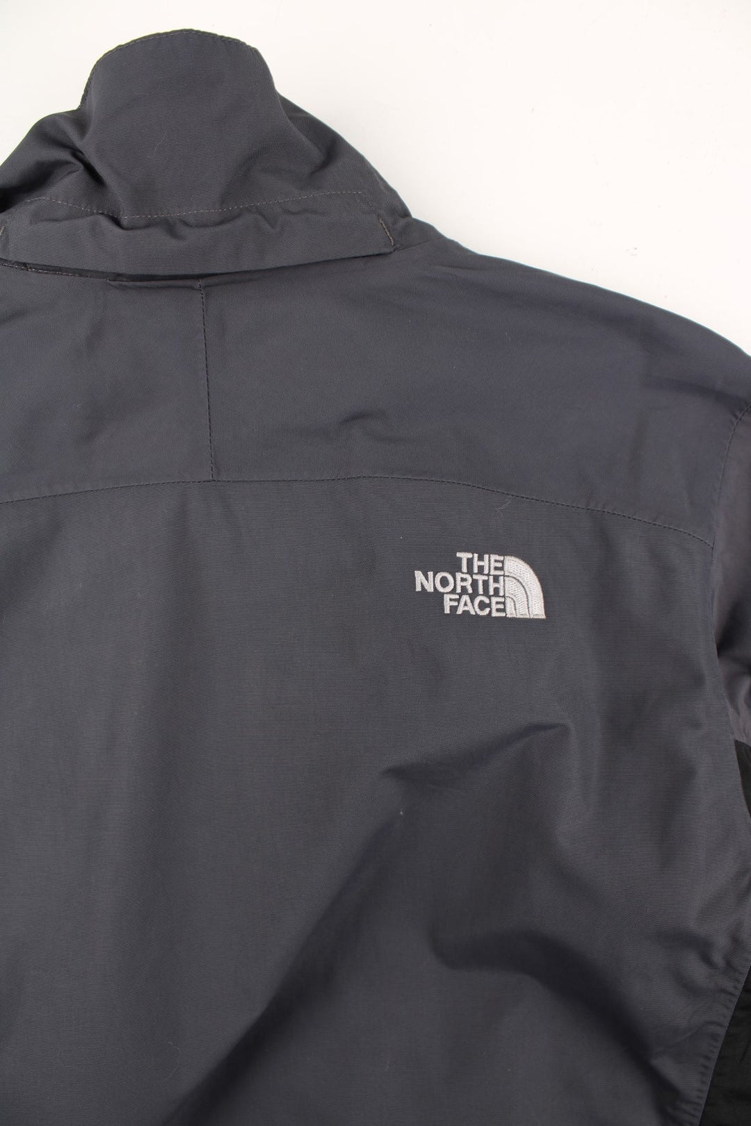 The North Face Jacket in a grey and black colourway. Zips up and has multiple pockets, and the logo embroidered on the front and back.