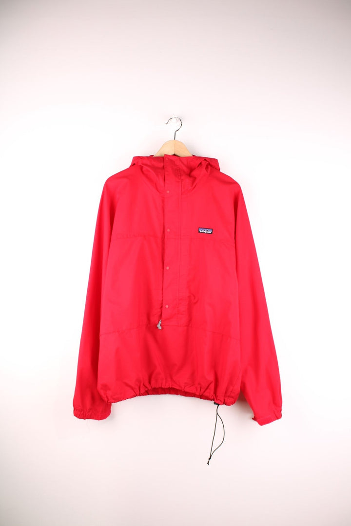 Patagonia lightweight hooded waterproof pullover jacket in red with 3/4 zip and snap closure.