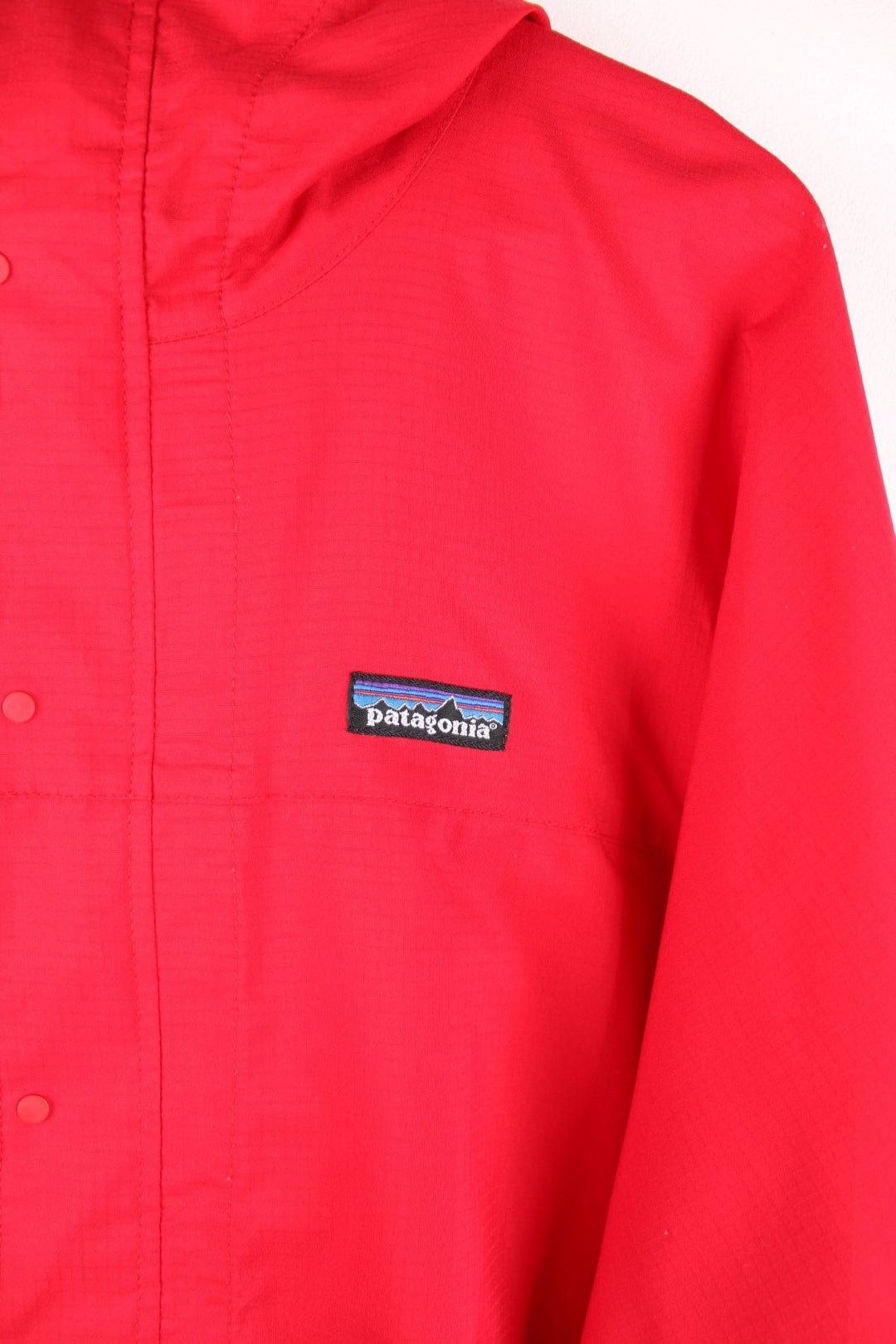 Patagonia lightweight hooded waterproof pullover jacket in red with 3/4 zip and snap closure.