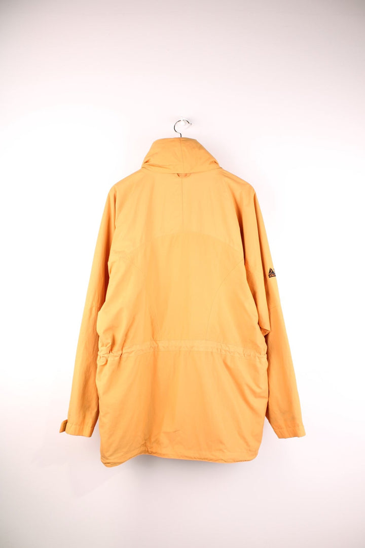 Vintage Lowe Alpine waterproof jacket in yellow with zip and snap closure, two front snapped pockets, an inside pocket, and a retractable hood. 