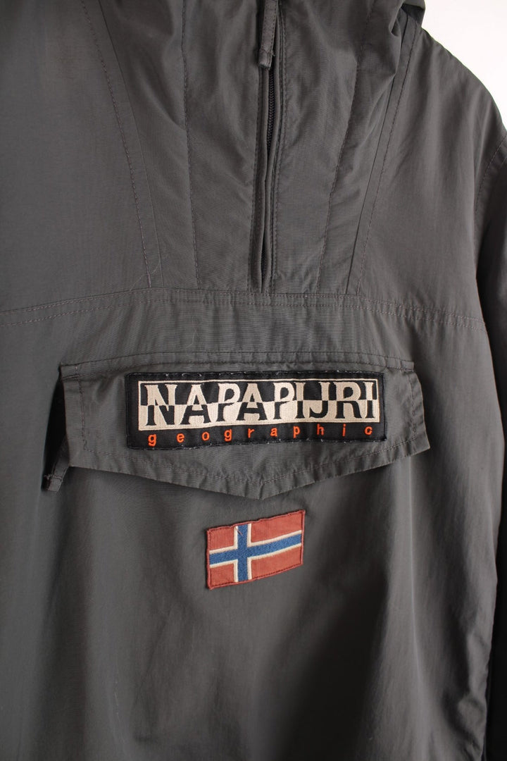 Napapijri hooded 1/4 zip pullover jacket in grey with front pouch pocket, side zip closure, various branded patches, and toggle adjusters in waistband.