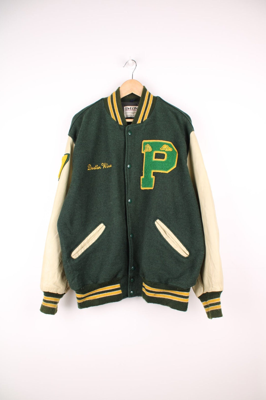 Vintage Delong, Placer Hillmen Wrestling varsity jacket in green and yellow, with beige leather sleeves and snap fastenings. Features embroidered letterman patch and numbers on the sleeve. 