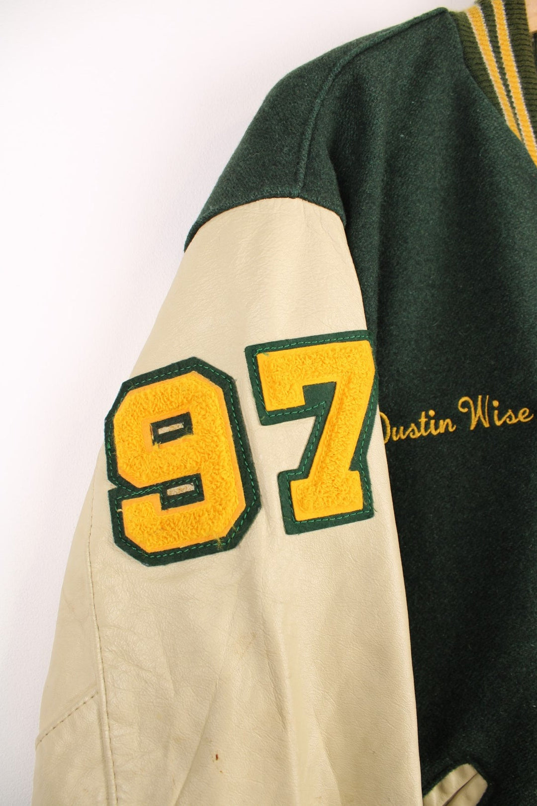 Vintage Delong, Placer Hillmen Wrestling varsity jacket in green and yellow, with beige leather sleeves and snap fastenings. Features embroidered letterman patch and numbers on the sleeve. 