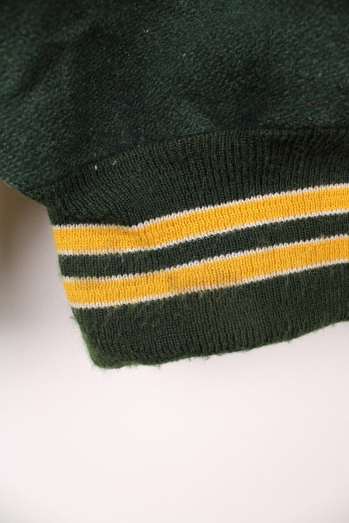 Vintage Delong, Placer Hillmen Wrestling varsity jacket in green and yellow, with beige leather sleeves and snap fastenings. Features embroidered letterman patch and numbers on the sleeve. 